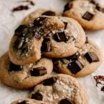 Stack of chewy chocolate chip cookies on parchment paper.