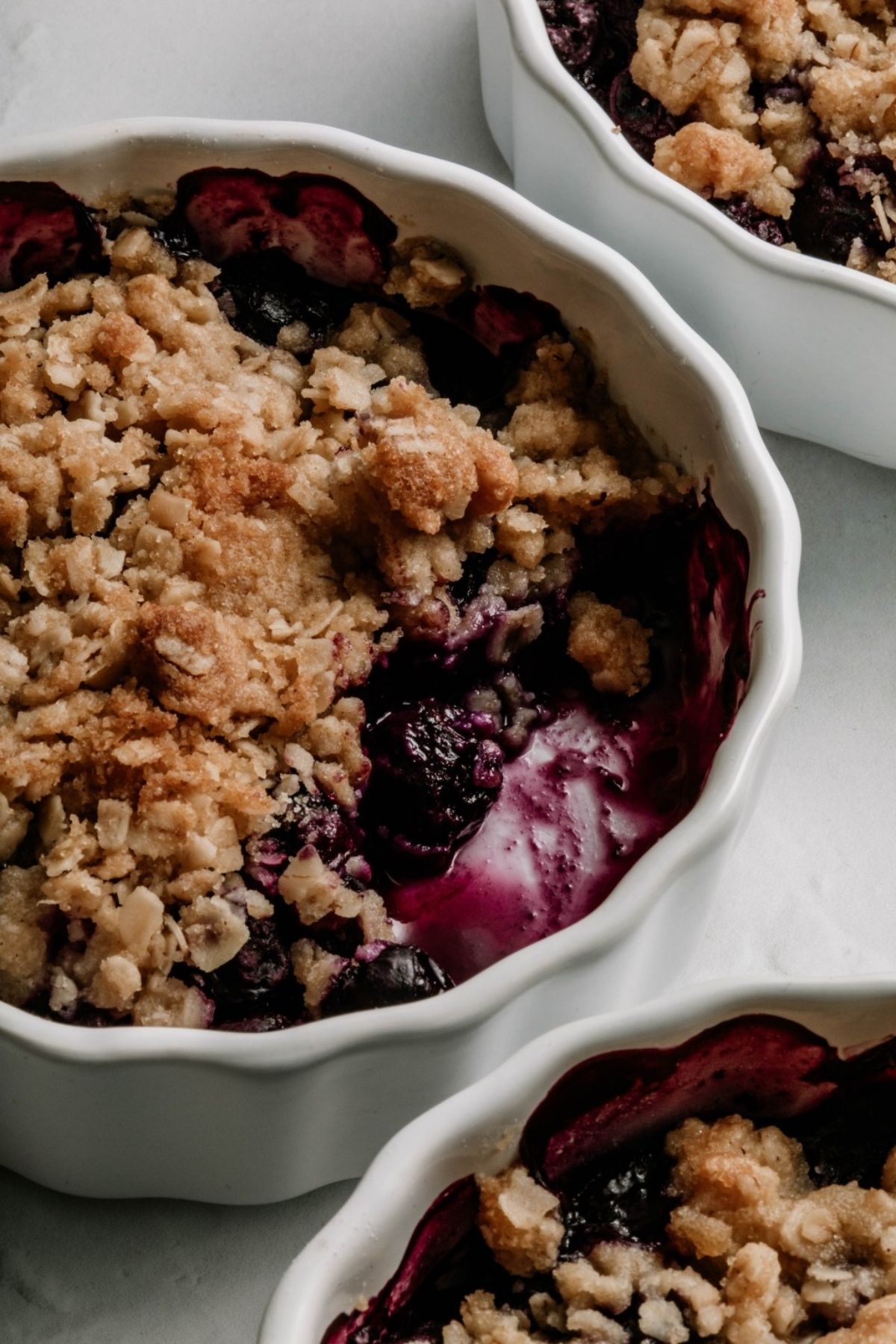 Close up of a single serving of blueberry crisp, with a few bites taken.