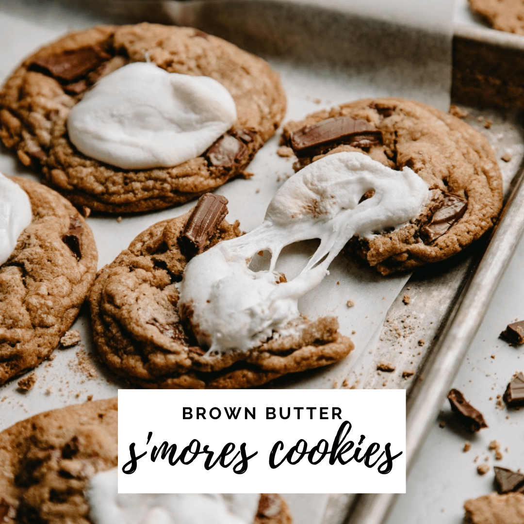 browned butter s'mores cookies on a pan, one pulled in two with gooey marshmallow pull.