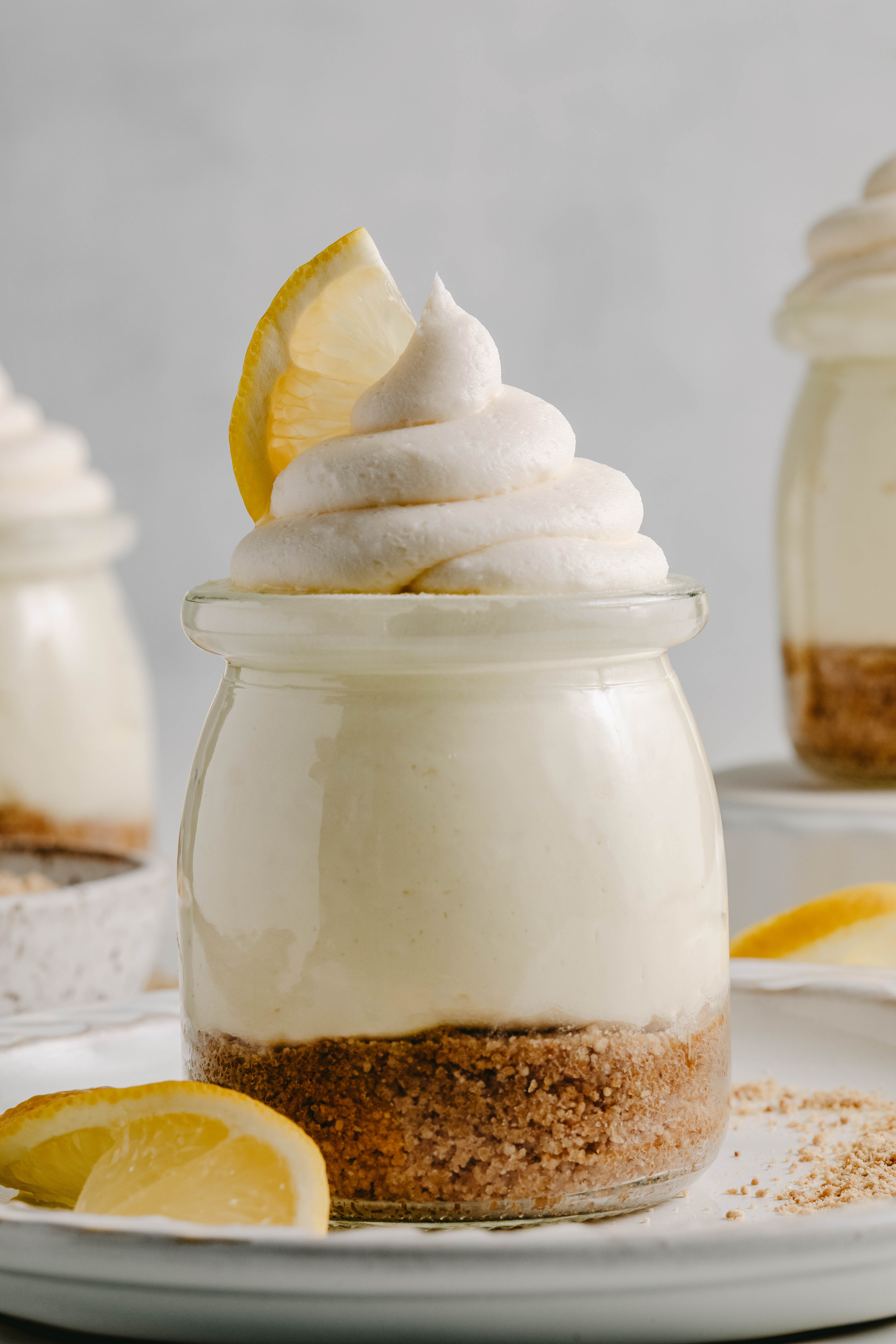 No bake lemon cheesecakes in a plate, garnished with lemon wedges and graham crumbs