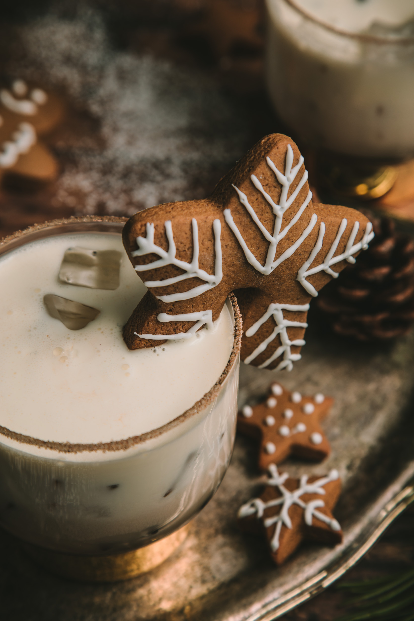 Gingerbread White Russian in a gold rimmed glass, garnished with a star shaped gingerbread cookie