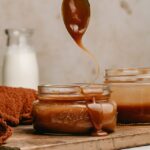 Drizzling 5 minute caramel sauce over a jar with a spoon.