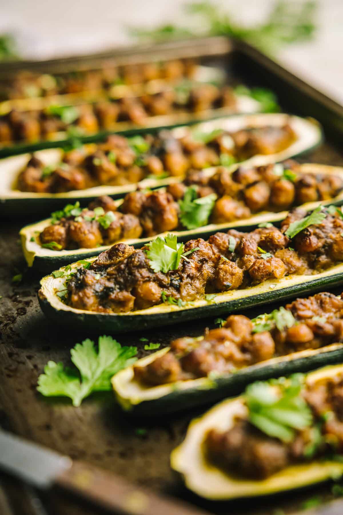 Close-up view of  a baking sheet filled with cooked chickpea curry stuffed zucchini boats.