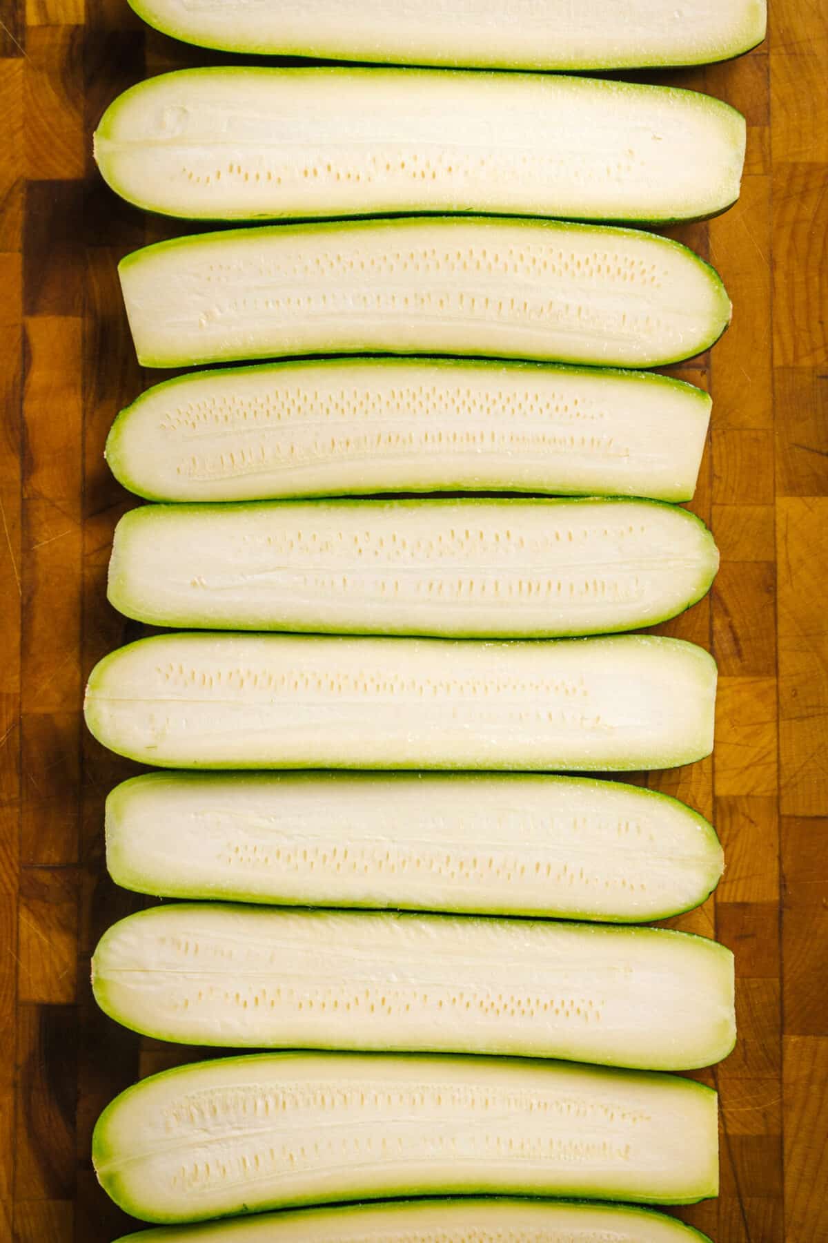 Overhead view of zucchinis cut in half, placed on a wood cuttingboard.